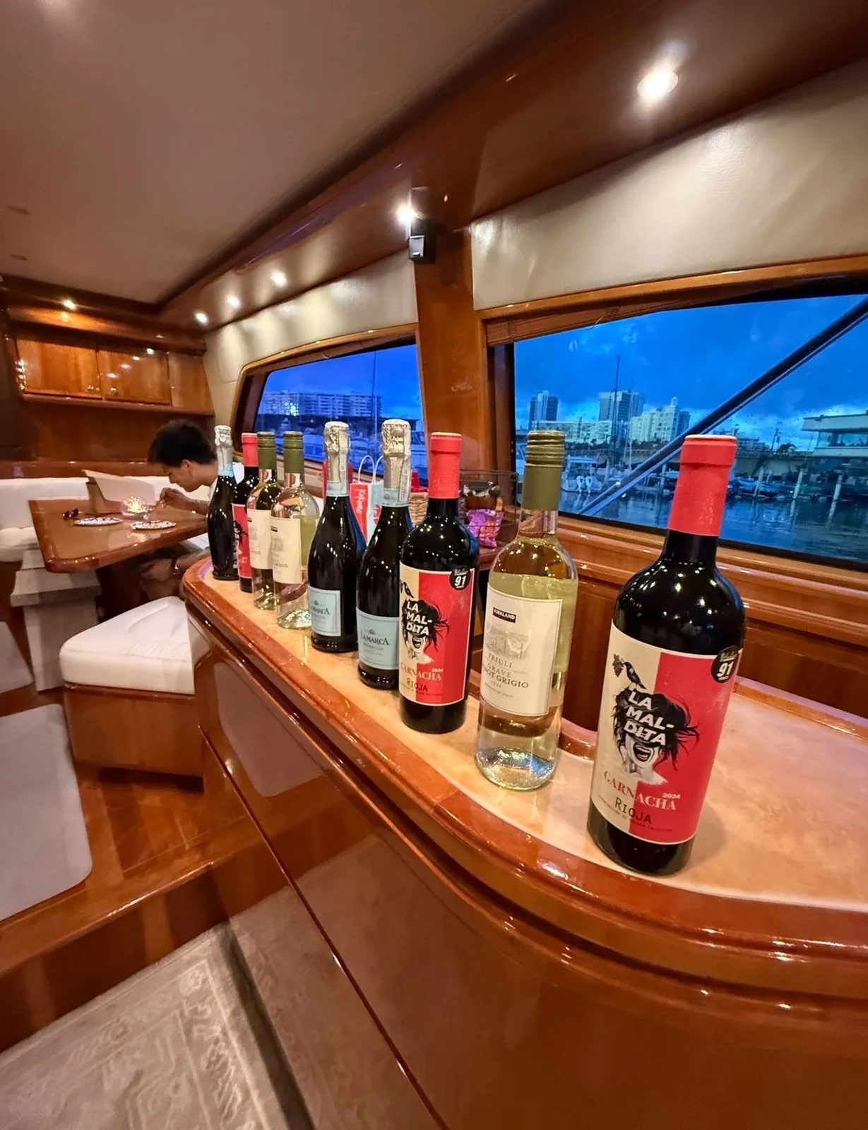 Wine and Prosecco bottles arranged on the Bertram 70 bar with marina lights at twilight