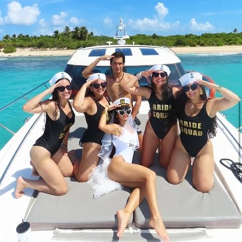 Bride Squad bachelorette group celebrating on the bow of a private yacht in turquoise Caribbean water near Fajardo, Puerto Rico