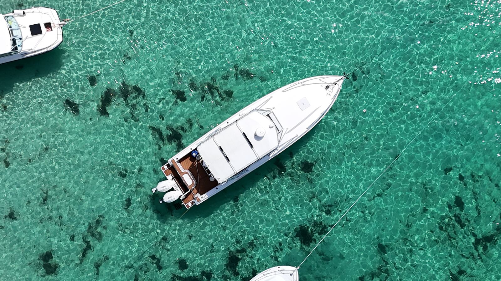 Contender 38 seen from directly above anchored on clear emerald water with the sand and reef visible below, Icacos, Puerto Rico