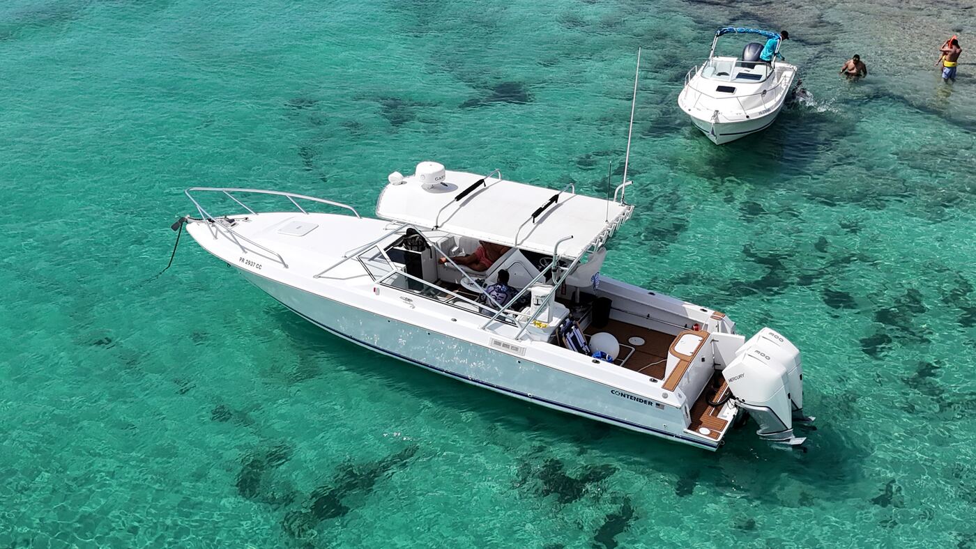 Contender 38 center console at anchor over a reef, twin Mercury outboards and teak cockpit seen from the air near Fajardo, Puerto Rico