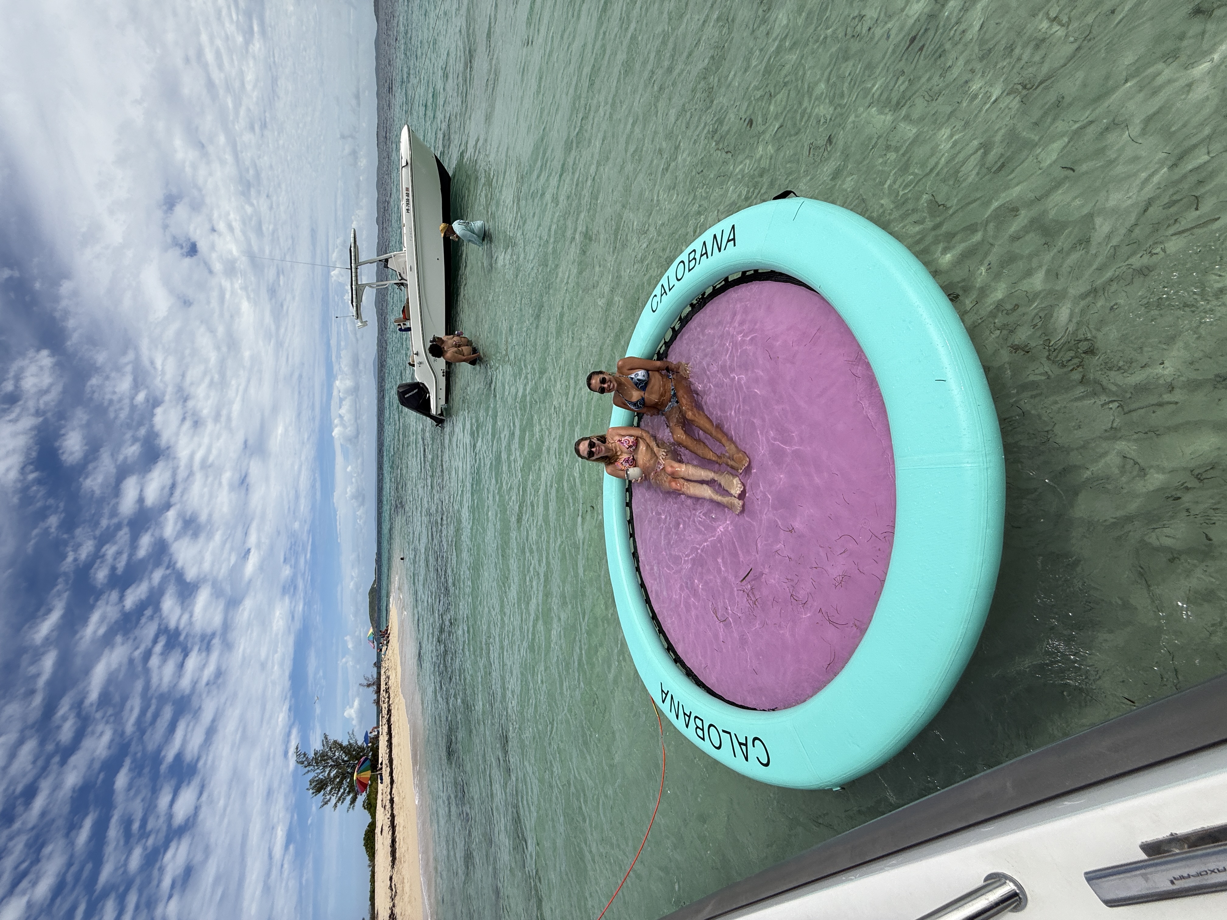Guests on Calobana floating mat at sandbar with center console boat in background