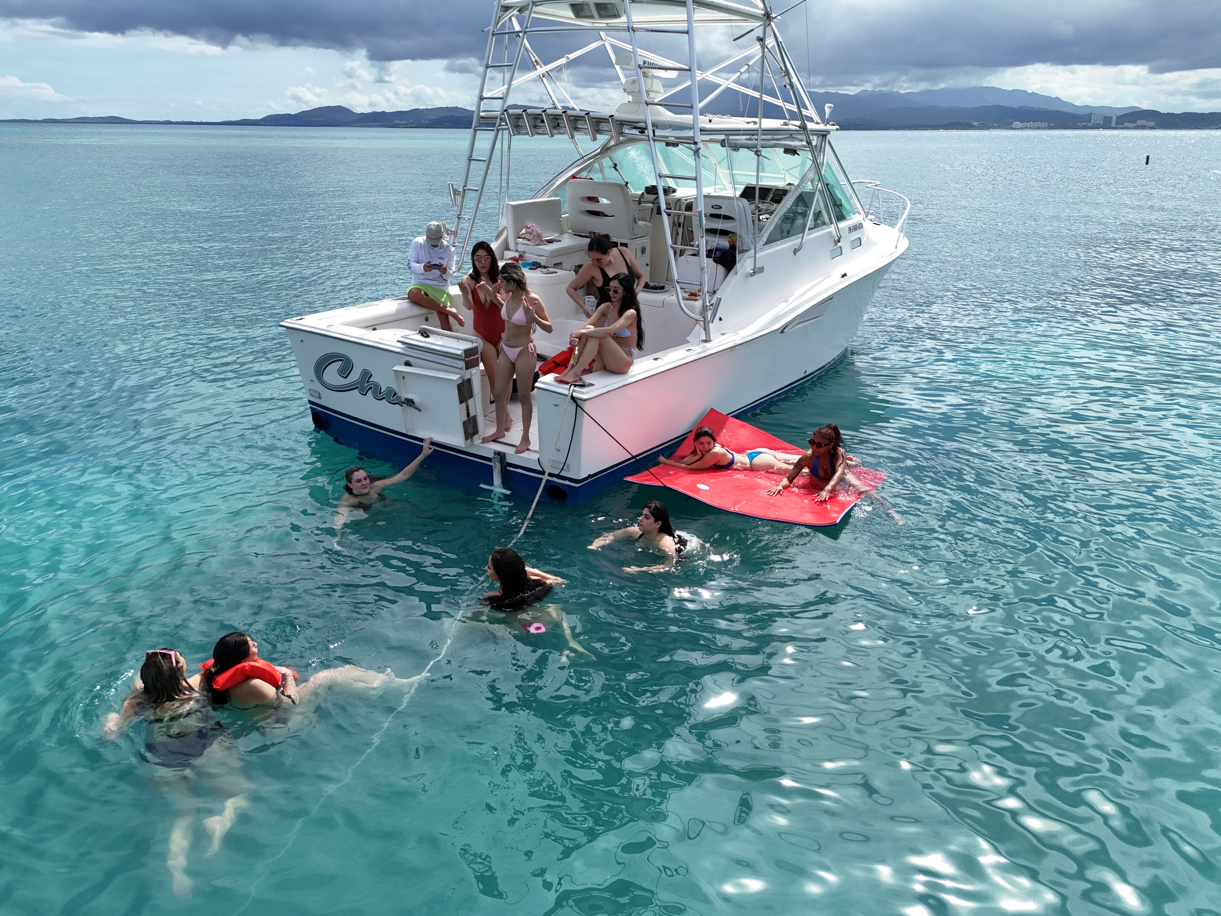Top-down aerial of Chu fishing yacht with guests swimming around