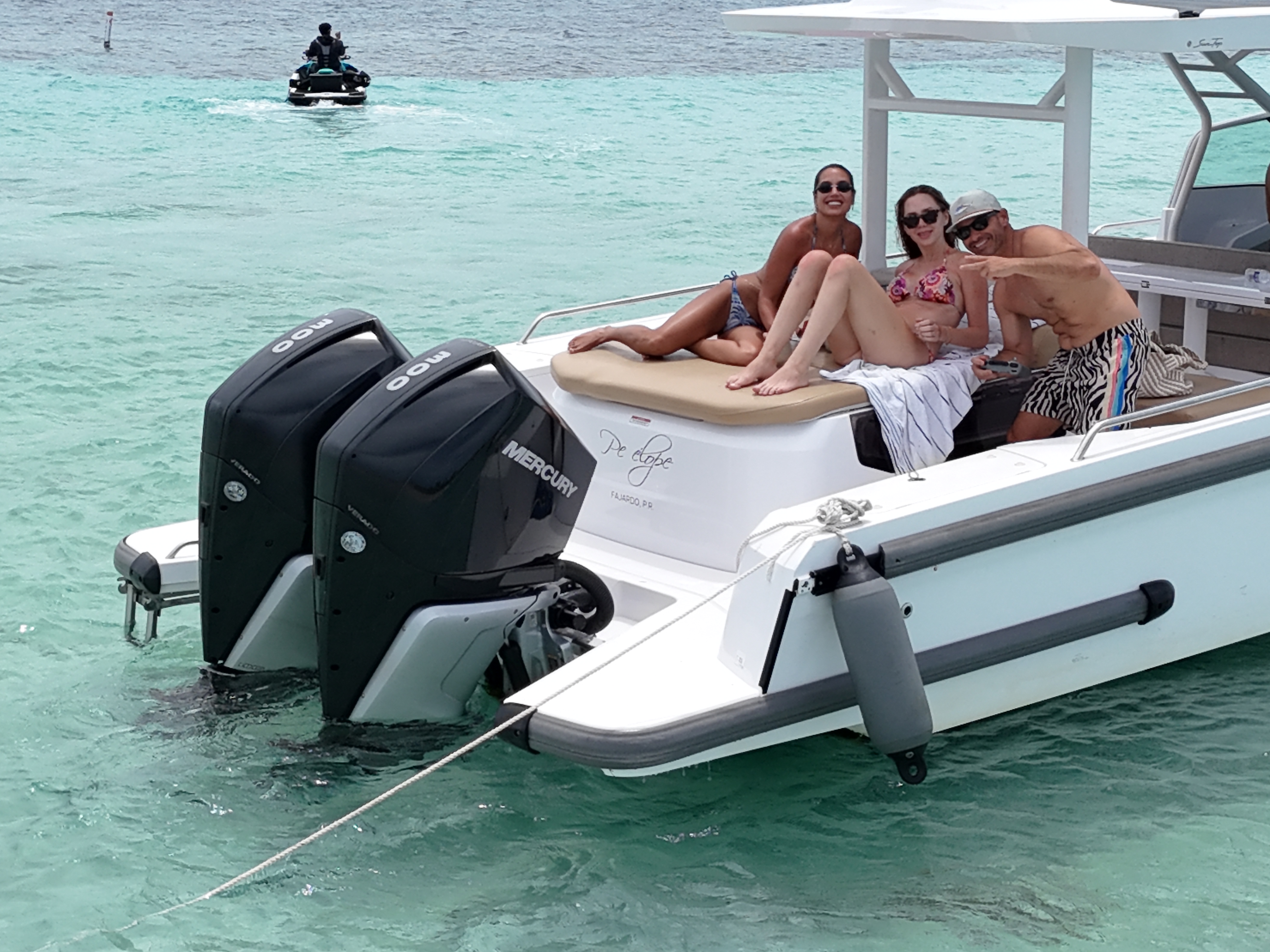 Guests lounging on Axopar yacht stern with jet ski in background