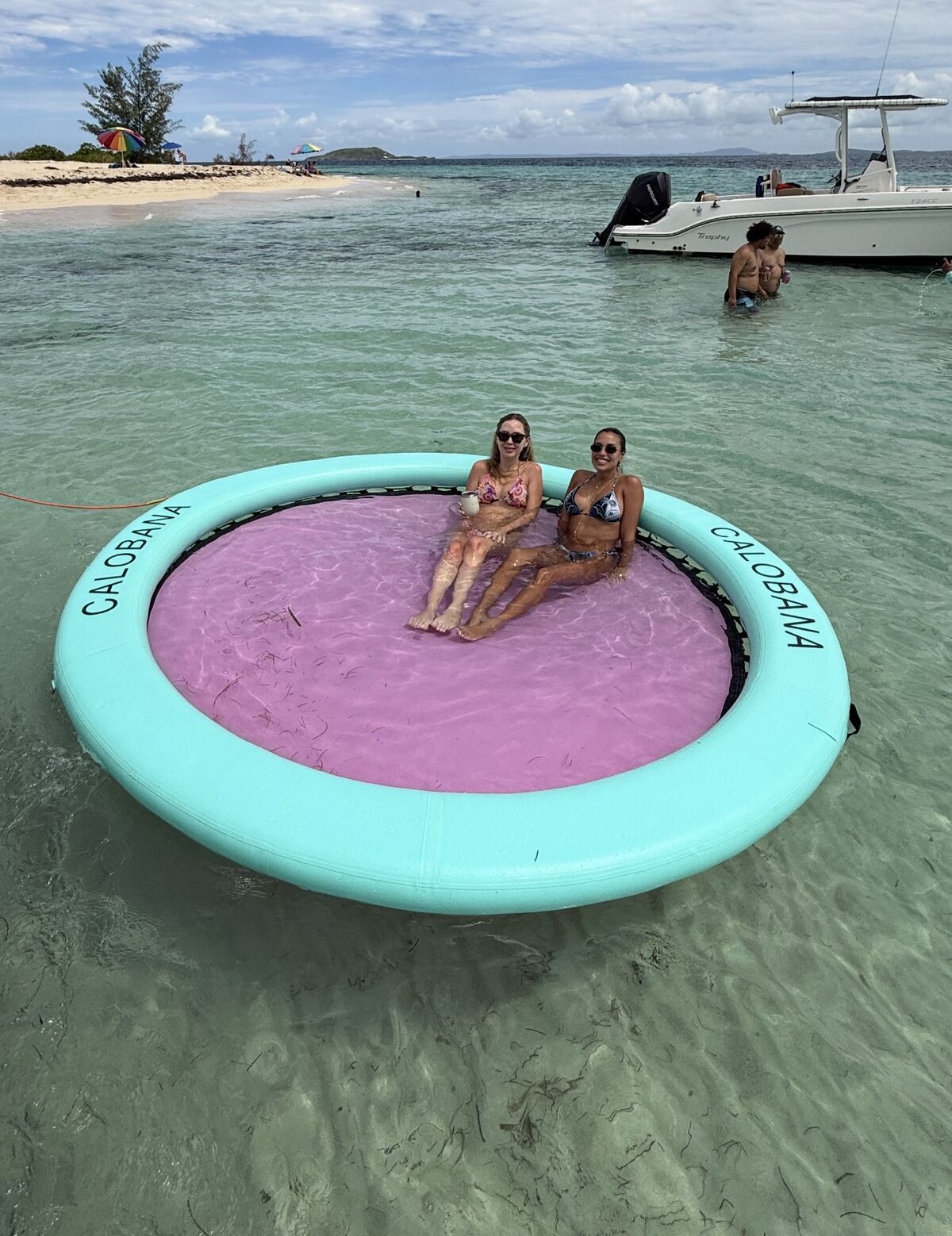 Two guests sitting in an inflatable floating cabana in shallow clear water off Icacos Island during a private boat charter from Fajardo, Puerto Rico