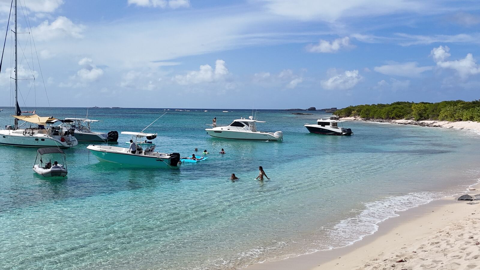 Clear turquoise shallows at Icacos Island with a sailboat and center console boats at anchor, a swim stop on private charters from Fajardo, Puerto Rico