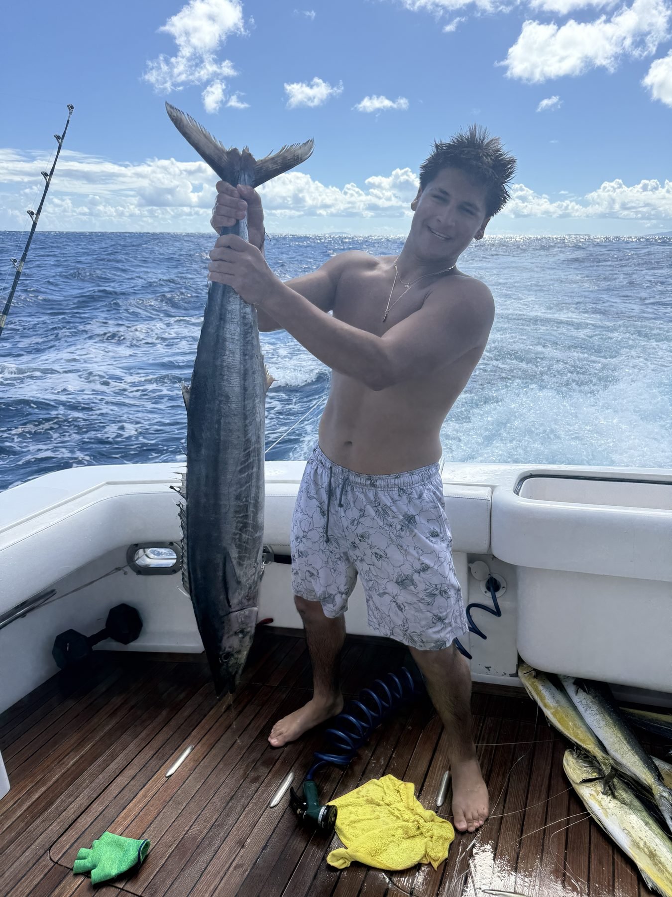 Angler holding a wahoo by the tail on the deck