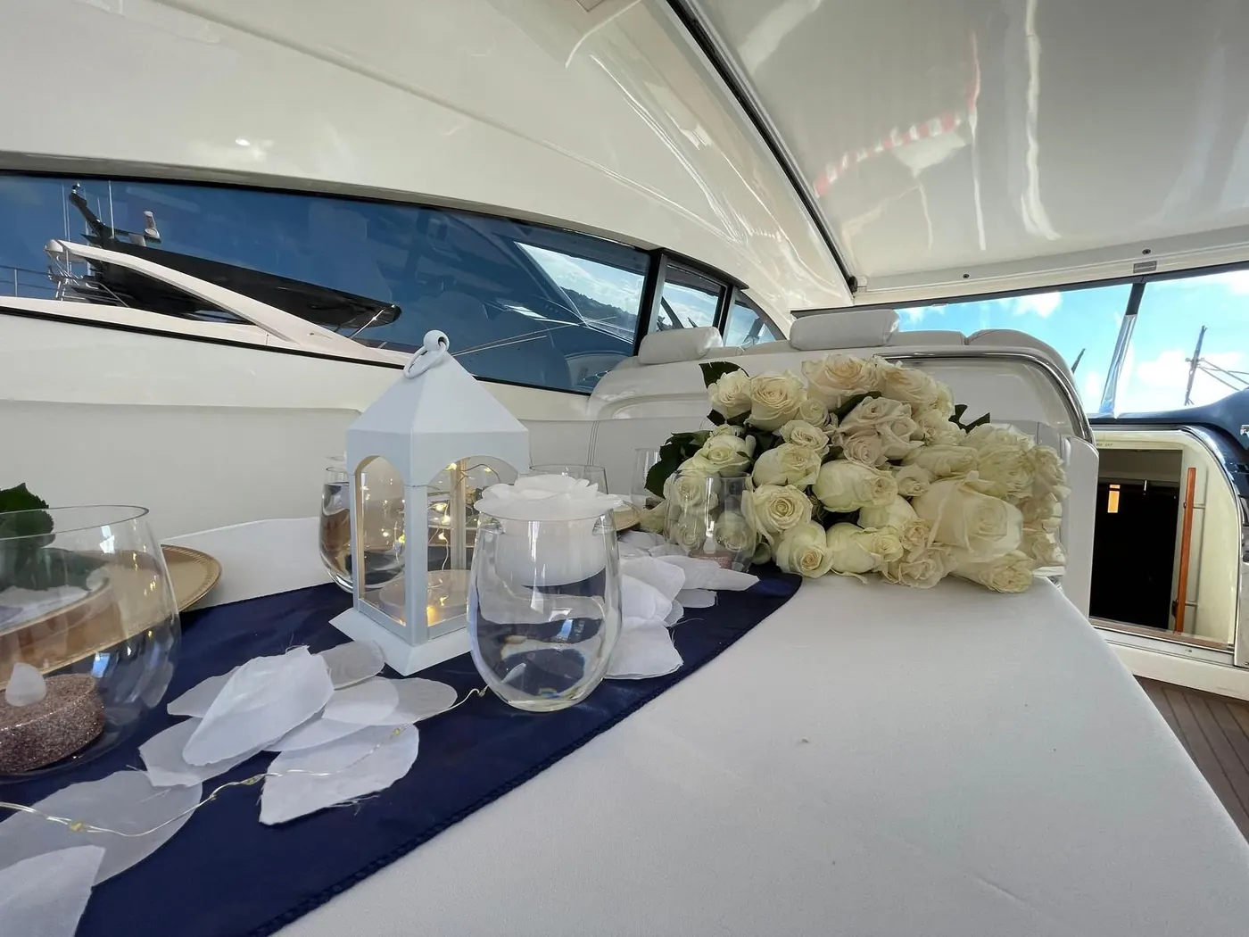 Romantic proposal setup onboard yacht with white roses, lanterns and rose petals
