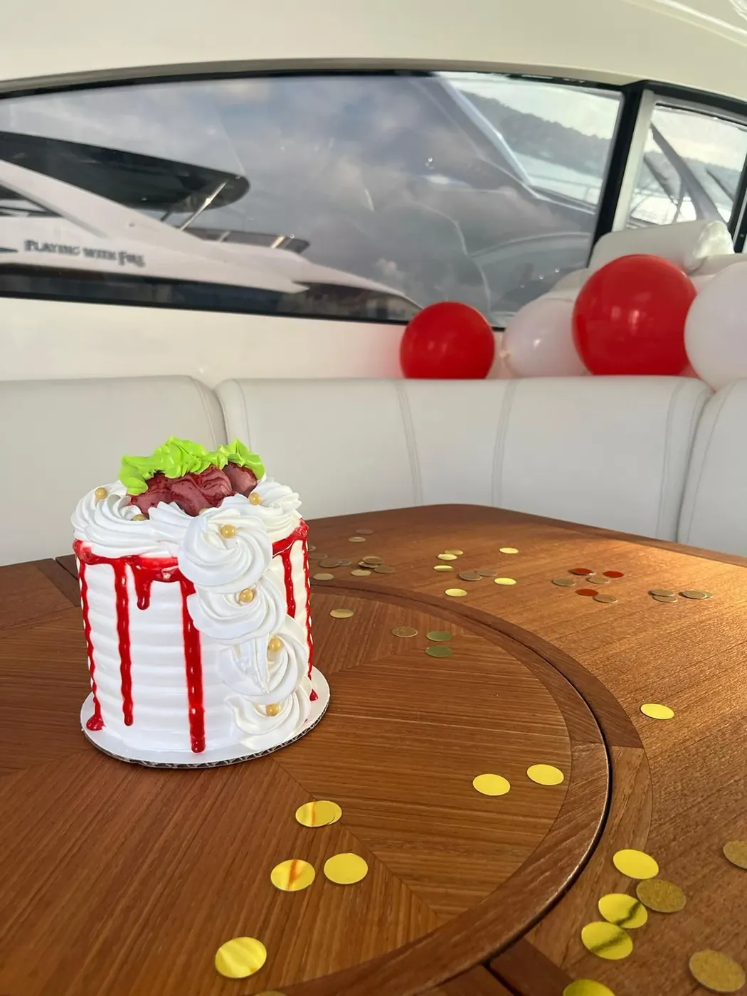 Custom birthday cake with red drip and balloons onboard yacht