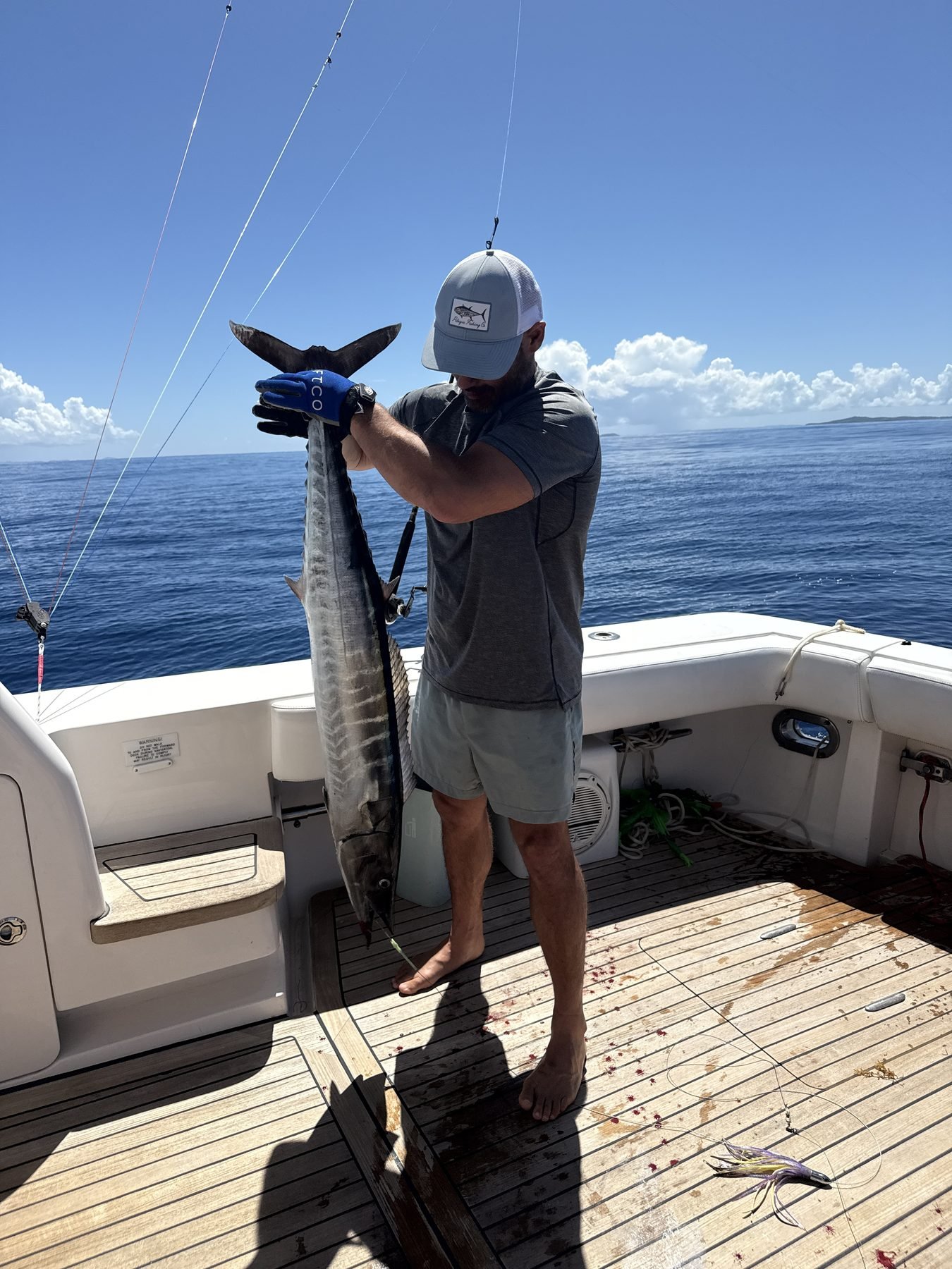 Mate holding a wahoo on the teak deck of the Bertram 70