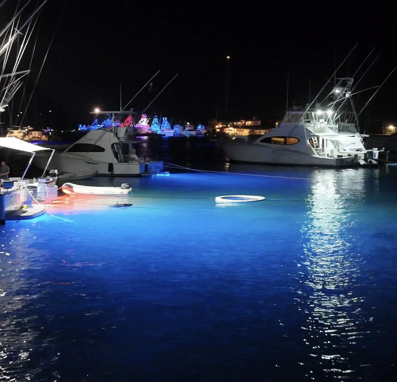 Deep blue underwater lights lighting the water around boats at anchor at night in Fajardo Puerto Rico