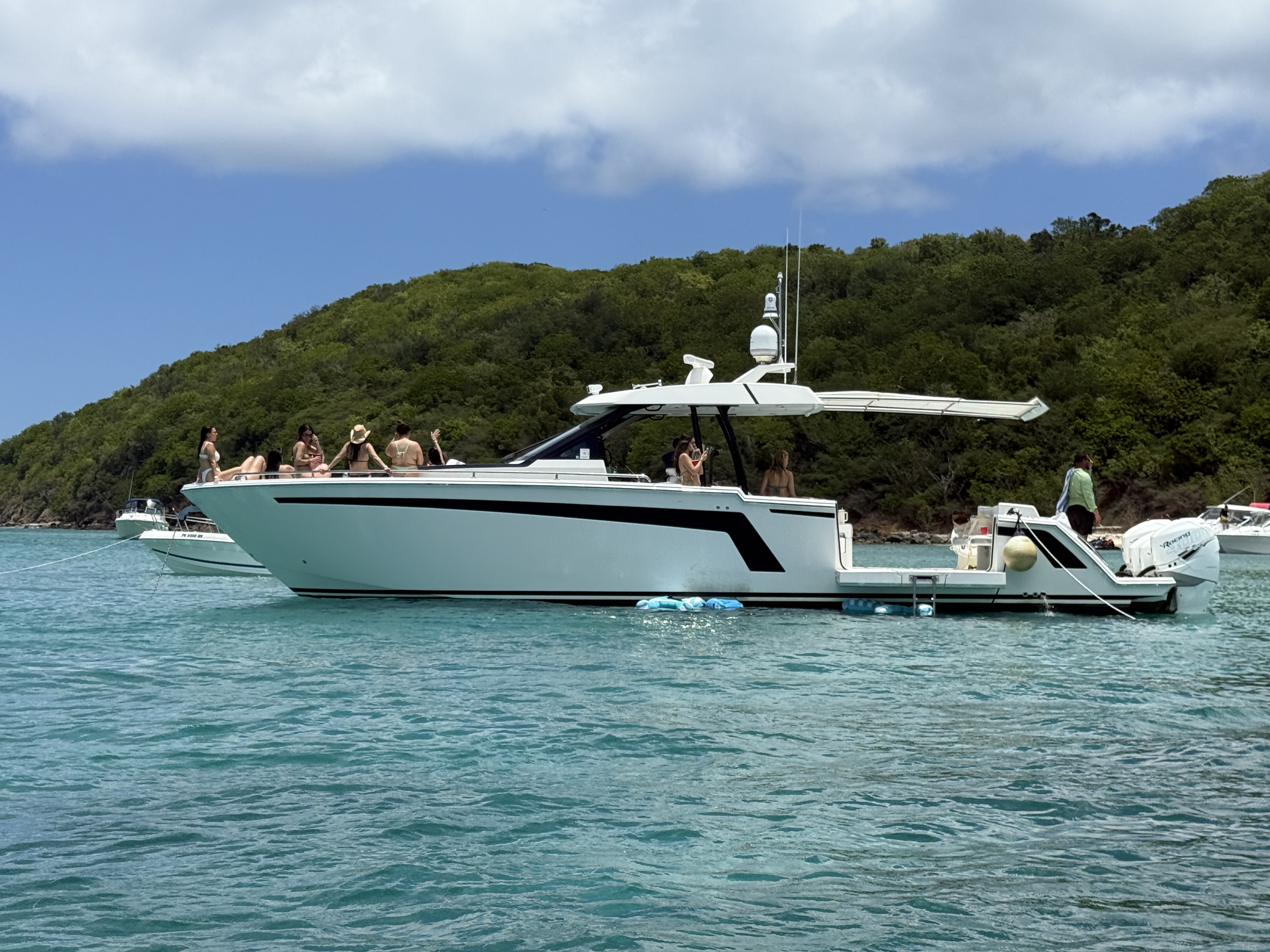 Group celebrating on the bow of an Ocean Alexander yacht anchored at a Caribbean sandbar
